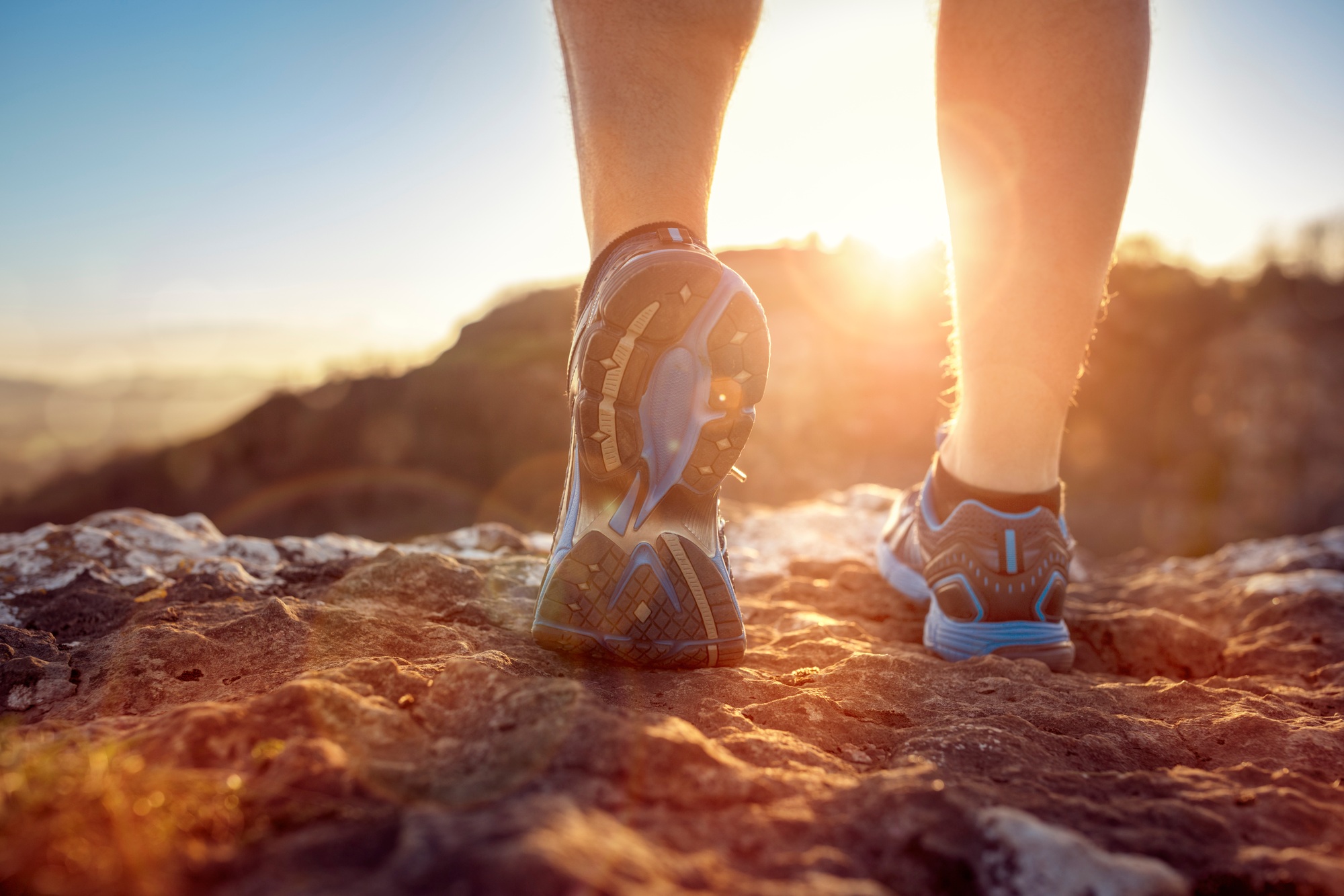 Runner feet running on trail looking at sunset